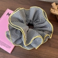 Détail d'un chouchou à carreaux noirs et blancs avec bords jaunes volantés - Grille Noir Blanc