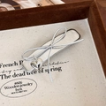 Close-up of silver bow hair clip with heart pendant on a beige canvas display tray - 25413B BB Clip