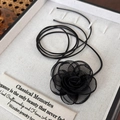 Detailaufnahme der schwarzen Mesh-Rosen-Halskette auf einem weißen strukturierten Display - Schwarze Mesh-Blume (25453B)