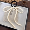 Detail of elegant cream bow hair tie with glossy pearl pendant on textured background - Beige Bowknot