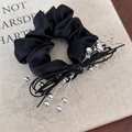 Dettaglio di un elastico scrunchie in raso nero con perle d'argento e lacci in pelle - Elastico Stile Nero (25491D) / Nero