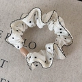 Detalle de coletero crema con lunares negros, bordes ondulados y cuenta decorativa - Blanco con lunares negros