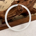 Detailed view of a creamy white round jadeite bangle on a Zen style wooden stand - White Plain Bangle / White