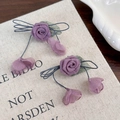 Primer plano de pendientes de rosas de tela morada con hojas y estilo retro francés - Flor Púrpura