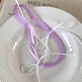 Detail of purple glass bead necklace featuring white silk bows on a white ceramic plate - Purple Beads (25544E)