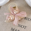 Dettaglio del fermaglio per capelli con fiocco in seta rosa, cuori e perle eleganti - Rosa