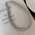 Detalle del collar de perlas grises con cierre metálico sobre tela de lino minimalista - Collar de Perlas Grises (25577B)
