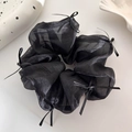 Detalle de coletero de organza negra con elegantes lazos de cinta en un fondo neutro - Negro