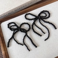 Détail d'un ornement en perles noires en forme de nœud avec pompons sur plateau - Trois nœuds en perles noires brillantes (25580C)
