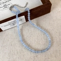Détail d'un collier de perles bleu marine avec fermoir mousqueton argenté sur tissu rustique - 4mm Collier