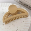 Détail d'une grande pince à cheveux beige mat sur une assiette en céramique blanche épurée - Jaune