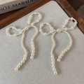 Macro shot of faux pearl bow shoe charms with elegant cream finish on linen background - Mixed Size Beads Bowknot