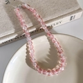Detailaufnahme der rosa und klaren Crackle-Glasperlenkette auf einem Keramikteller - Buntes Rosa (10mm)