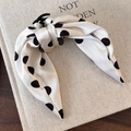 Detailaufnahme einer Polka-Dot-Haarklammer aus Seide mit Schleife auf einem Buch - Weiß Gepunktet
