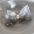Détail de la pince à cheveux papillon en organza gris avec perles sur une assiette - Bleu (25608B)