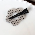 Gros plan d'une pince à cheveux florale en acrylique à pois noirs sur une porcelaine - Base Blanche Point Noir Fleur
