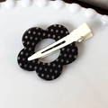Gros plan d'une pince à cheveux fleur à pois noirs et blancs sur une assiette décorative - Base Noire Point Blanc Fleur