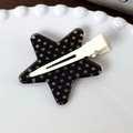 Gros plan d'une pince à cheveux en forme d'étoile à pois sur une assiette blanche - Base Noire Point Blanc Étoile