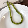 Close-up of green beaded stone necklace with silver clasp on white ceramic plate - 8mm Necklace (25664B)