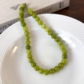 Close-up of green beaded necklace with silver lobster clasp on a white plate - 10mm Necklace (25664C)