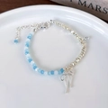 Dettaglio di bracciale con perle blu, sfere d'argento e ciondolo a forma di fiocco - Bracciale in Cristallo Stile Argento Spezzato