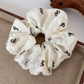 Dettaglio di uno scrunchie bianco stile balletto con fiocchi neri e piccoli strass - Grande (14cm)