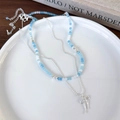 Dettaglio della collana di perline blu con fiocco d'argento su un piatto di ceramica - Collana a Doppio Strato Con Fiocco