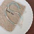 Dettaglio della collana di perle con ciondolo a fiocco argento su carta vintage e piatto - Collana di Perline e Perle Con Fiocco