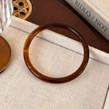 Macro detail of amber acetate bangle with vintage texture on a beige linen display tray - Amber Thin Style (25722B)