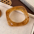 Macro view of geometric amber resin bangle with marble texture on beige fabric base - Irregular Geometric Style (25722F)