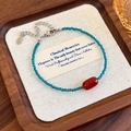 Detailopname van vintage kralenketting met rode agaatkraal en blauwgroene facetstenen - Blauw Kristal Armband