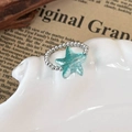 Detailed close-up of a silver beaded ring featuring a translucent mint green starfish - Starfish Style (25765A) / Silver and Light Blue