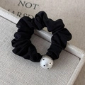 Close-up of a black pleated scrunchie with a polka dot pearl bead on beige linen tray - Small Pearl Style (25778A) / Black