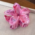 Detail of pink marble acetate plumeria hair claw clip on a textured beige tray - Dazzling Red