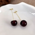 Detailed macro view of cherry-shaped drop earrings with deep red resin and golden metal stems - Dark Red Small Cherry