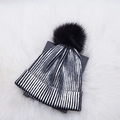 Close-up of black and silver striped knit beanie with a fluffy faux fur pompom detail - Adult / Silver