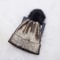Golden knit beanie hat with black faux fur pom-pom on white faux fur background - Adult / Gold