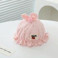 Detail der rosa Spitzenhaube für Babys mit Hasenohren, Plüschbällen und Kirschschleife - Einheitsgröße / Rosa