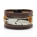 Detailed macro shot of vintage multi-layer leather bracelet with silver feather and rhinestones - Coffee