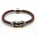 Nahaufnahme von braunem Lederarmband mit silbernen Totenköpfen und Magnetverschluss - Gun Black und Braun