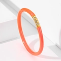 Detalle de una pulsera de gelatina naranja con dije de calavera dorada y cristales - Naranja Neón