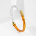 Detalle de brazalete bicolor con resina naranja, relieve dorado y marco de metal plata - Oro + Plata