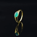 Anello in acciaio dorato con pietra verde ovale su una superficie riflettente nera - Oro-Blu