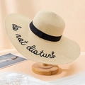 Detail showing beige straw sun hat with black Do Not Disturb embroidery on wide brim - One Size / Beige