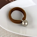 Detailopname van de koffiebruine haarelastiek met een zilveren metalen bolvormige bedel - Middelgrote Bal / koffiekleur