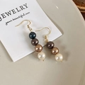 Detailopname van retro oorbellen met kleurverloop parels en gouden Franse haakjes - Asymmetrische Oorhaak (24333A)