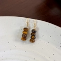 Close-up of vintage tiger eye stone beaded earrings with gold hooks on a ceramic dish - Tiger Eye Style (24356C)