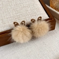 Close-up of brown plush butterfly earrings with soft fur balls and warm texture - Khaki