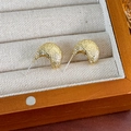 Primer plano de pendientes dorados con textura de lava en un joyero de madera - Estilo en Forma de C Dorado Martillado Vintage / Dorado