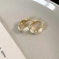 Detailed view of luxury gold round earrings with white enamel and sparkling rhinestones - Beige